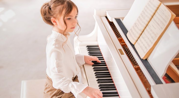 Little girl playing piano indoors